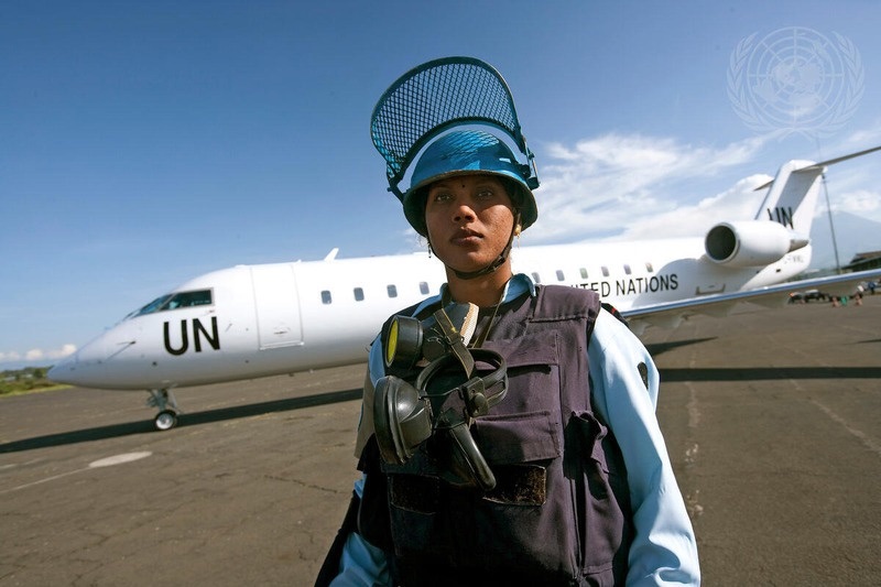 A peacekeeper on an airfield beside a UN aircraft